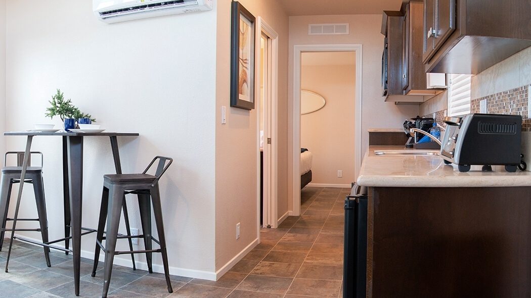 Panorama of 1 bedroom cottage interior showing dining, kitchen, and hall to bedroom